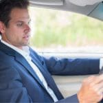 Man In A Suit Using A Cell Phone While Driving.